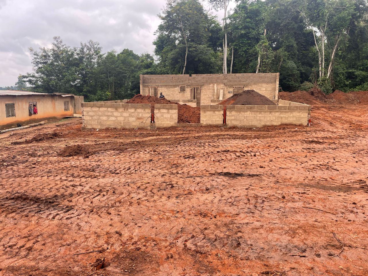 Low block walls on freshly cleared, muddy ground, with mounds of excavated earth inside.