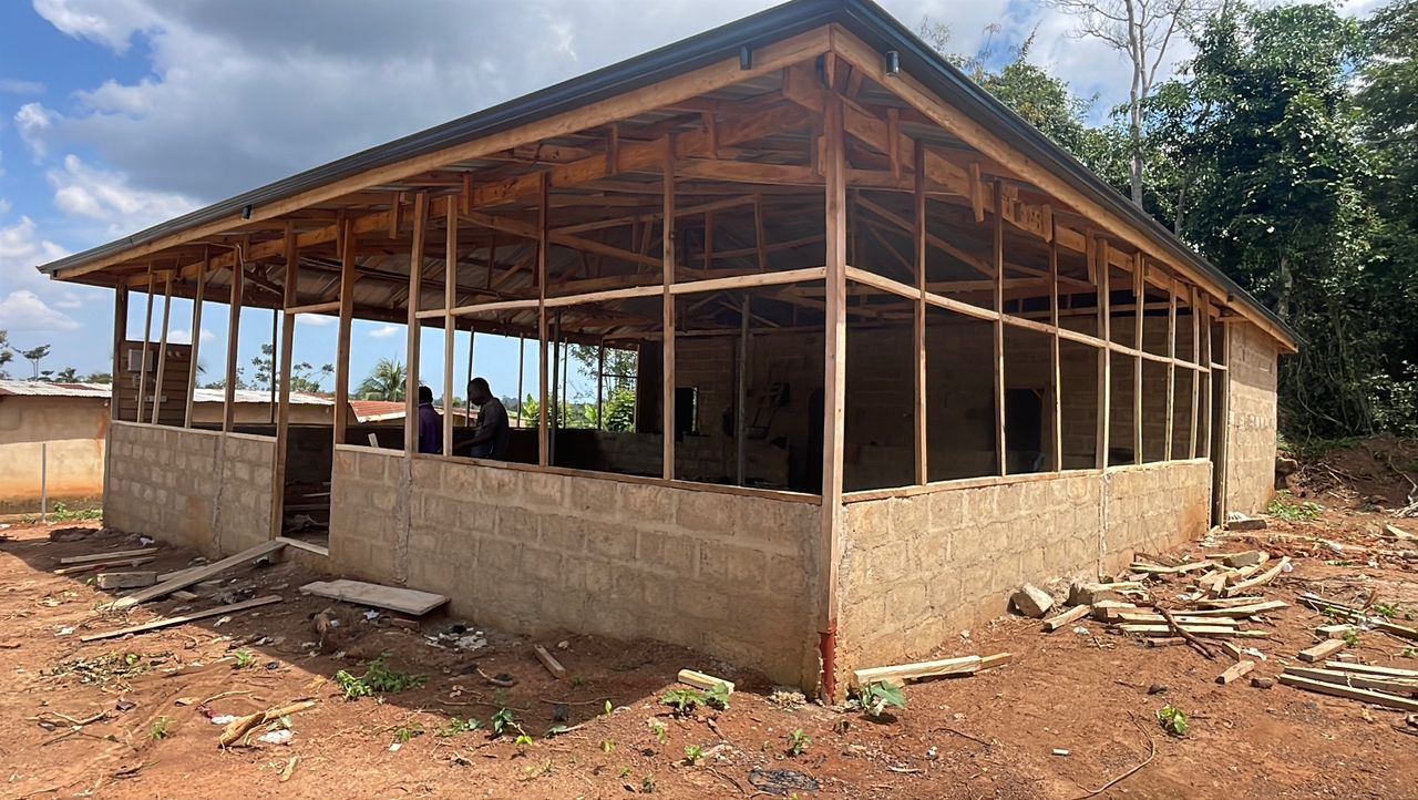 The main hall with its roof complete and wire-mesh window bays going in around the block walls.