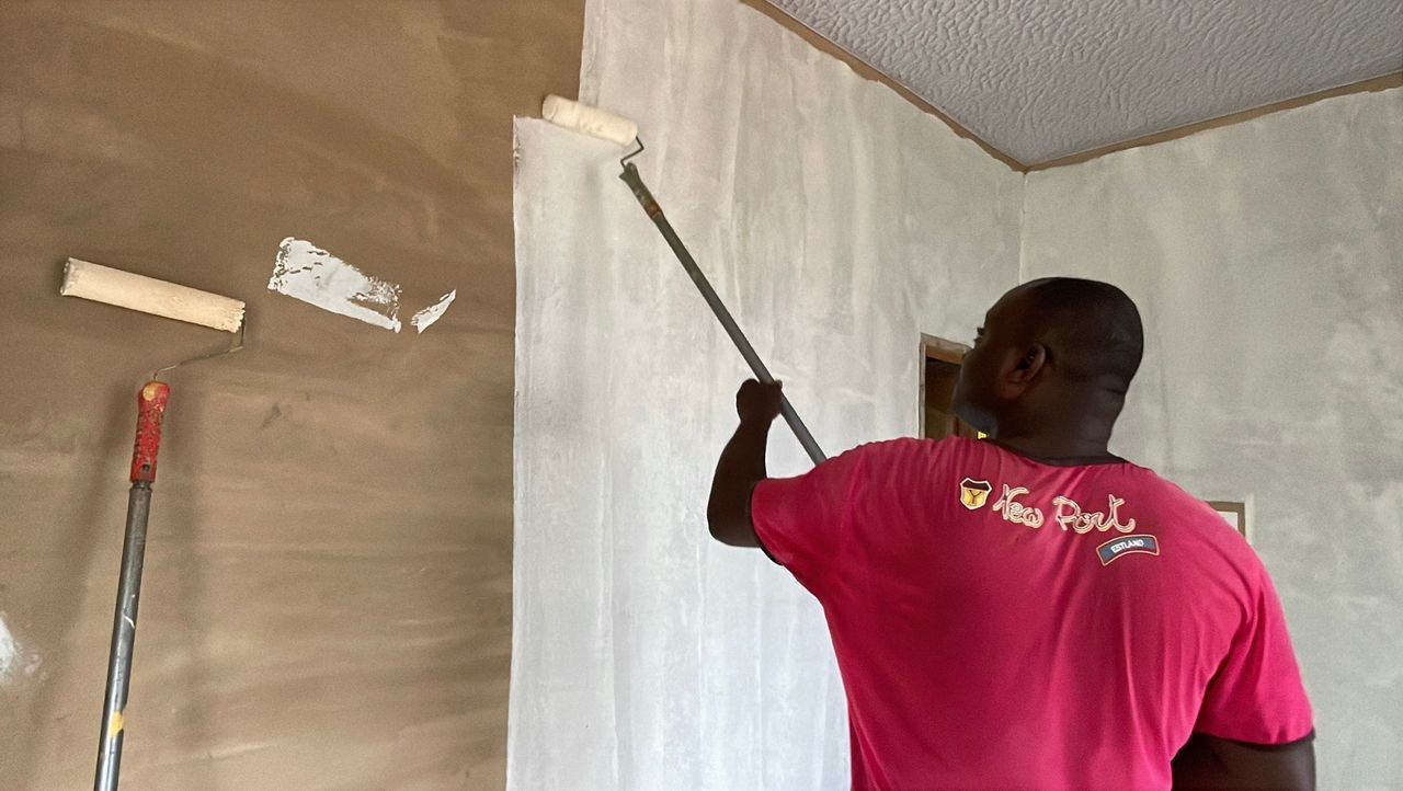 A worker applying a skim coat of plaster to an interior wall.