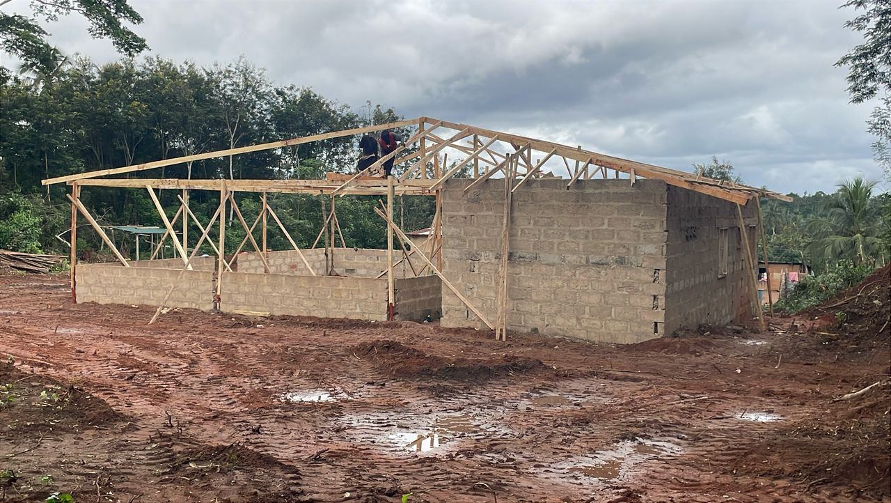 Timber roof trusses going up over the block walls of the main hall.